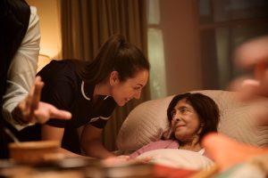 Nurse attending to lady in bed at home.
