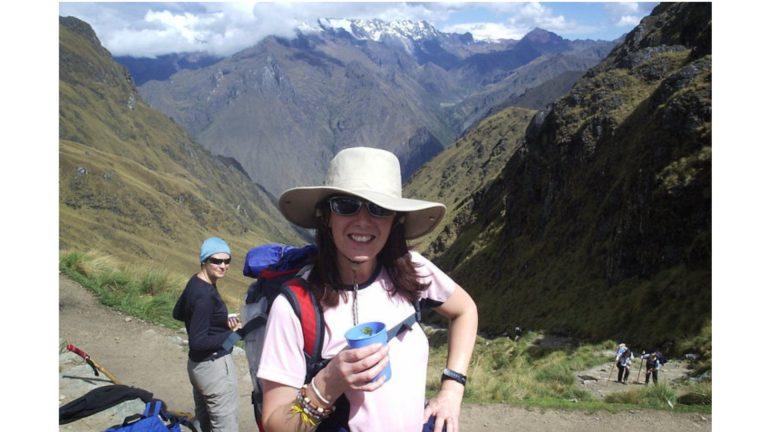 Michelle wearing a sun hat and smiling at the camera in front of mountains in Peru.